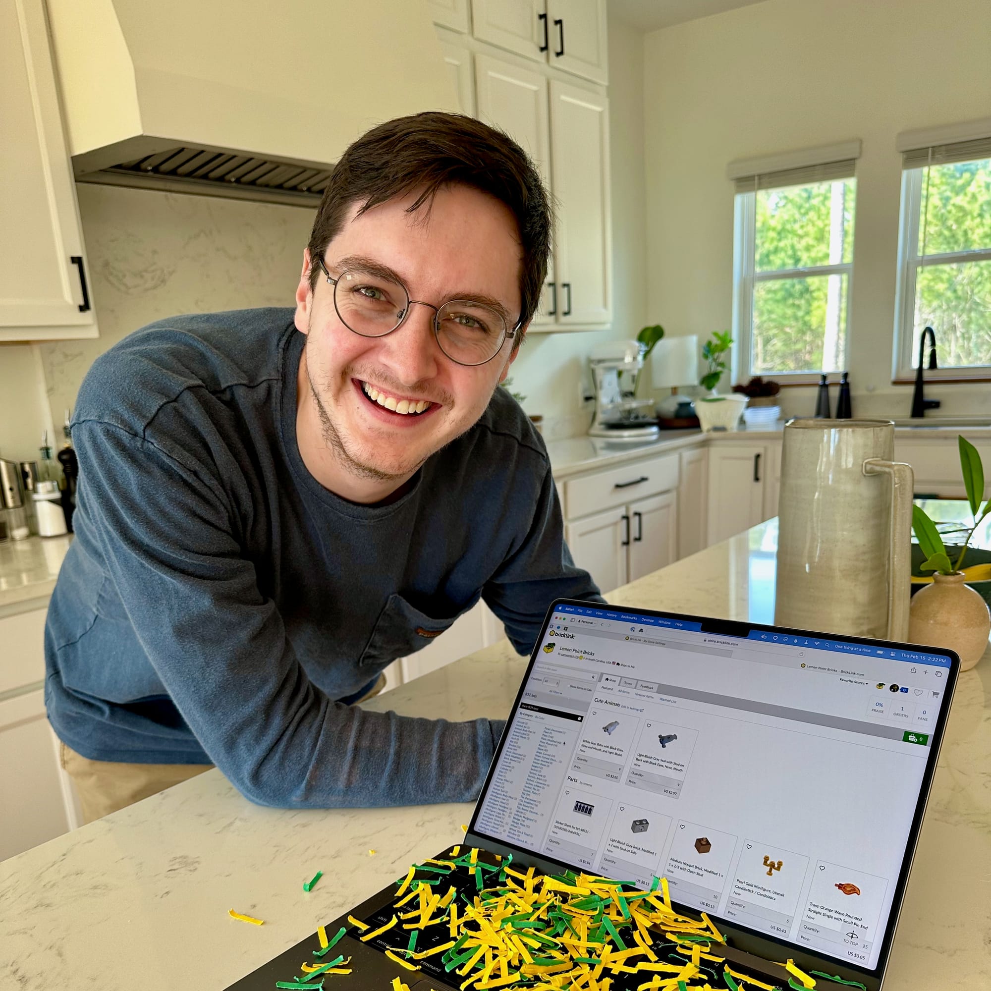 Man posing with laptop covered in yellow and green confetti showing a newly opened BrickLink store