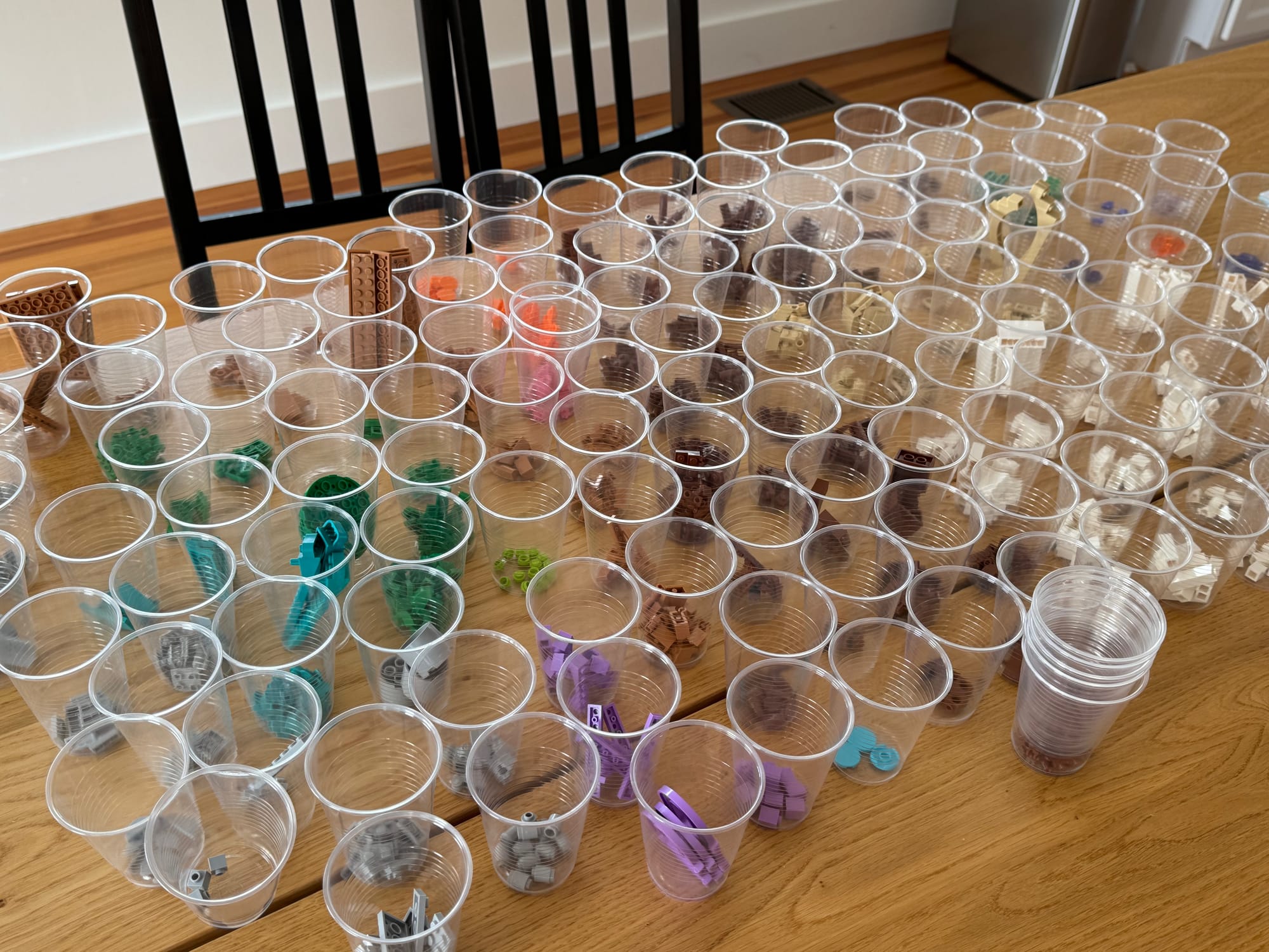 LEGO pieces separated into small plastic cups based on color and part type